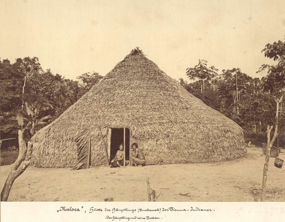 Fotografia antiga de uma maloca indígena com moradores na entrada, relevante para história do Brasil no ENEM.
